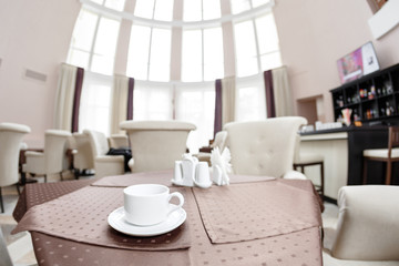 Coffee white cup for breakfast in restaurant with hotel background. Breakfast concept