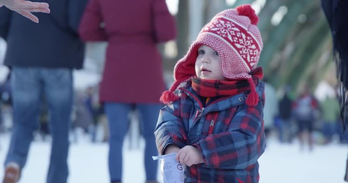 Toddler boy reaches for snack on rideau canal during winter festival - isolated shot