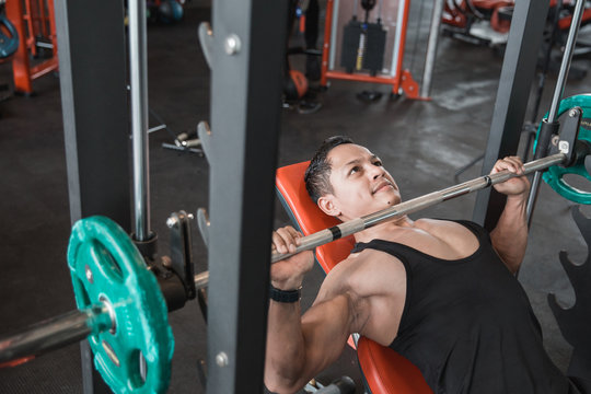 Muscular bodybuilder bench press workout with smith machine
