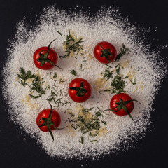 A pizza drawing on a black background made from flour and tomatoes. Concept