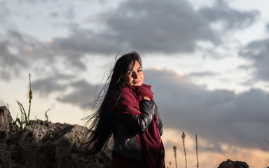 Model on the beach at sunset on a windy day with hair blowing.