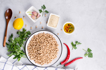 Main ingredients for making hummus, chickpea, lemon, garlic, sesame, oil, pepper, parsley top view. Food background with copy space