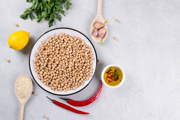 Main ingredients for making hummus, chickpea, lemon, garlic, sesame, oil, pepper, parsley top view. Food background with copy space