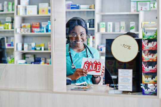 Two african american pharmacist working in drugstore at hospital pharmacy. African healthcare. Cashier holding sale.