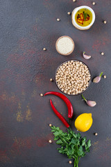 Ingredients for cooking hummus. Chickpeas, sesame seeds and oil. On dark background