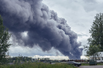 dangerous clouds of black smoke closeup from the burning of the factory at sunset of a summer day