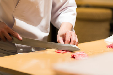 Obraz na płótnie Canvas Chef cook making sushi Sashimi with sharp knife on the cutting board