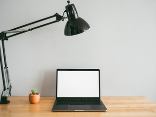 Laptop and some stationary tools on wooden work desk with empty gray wall as background. Concept of workspace and minimal office.