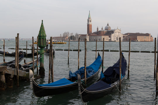 Parked covered gandolas on a pier at the sea with view on the San Giorgio Maggiore cathedral