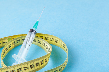 Syringe with a needle and yellow measuring tape. Injections for body beauty and weight loss. Drug...