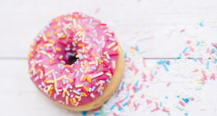 Pink donuts with sprinkles on wooden table