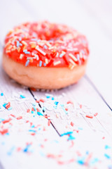 Pink donuts with sprinkles on wooden table