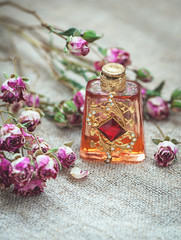 Obraz na płótnie Canvas Dry tea roses and vintage perfume bottle on the sackcloth