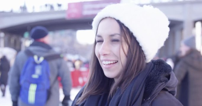 Woman skating on rideau canal in Ottawa turns and laughs - out of focus crowd behind her