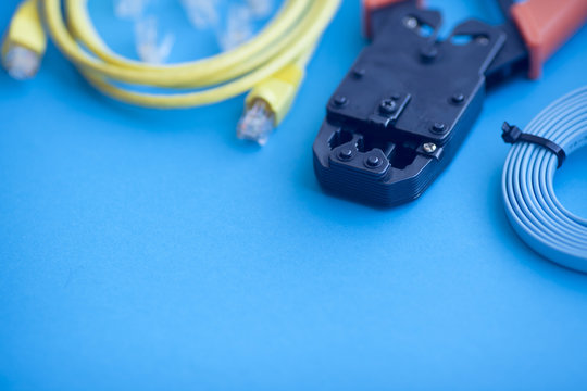 SKS and engineering concept. Set of connectors, ethernet and console cables, crimp tool on the blue background. Top view. Space for a text. Close up.