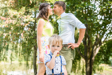 Fototapeta premium Young happy caucasian couple with little child boy. Parents and son walking and having fun together. Mother and father playing with toddler outdoors. Family, parenthood, childhood, happiness concept.
