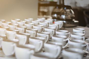 Many rows of white ceramic coffee or tea cups, in hotle