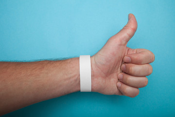 Empty event ticket wrist band design. White blank paper wristband, bracelet mockup on blue...
