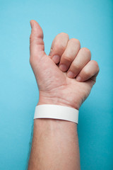 Blank mockup bracelet on man hand, isolated on blue background. Concert paper wristband.