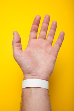 Blank mockup bracelet on hand, isolated on yellow background. Concert paper wristband.