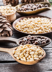 Pine nuts in the spoons on the wooden table. Macro. Organic food.
