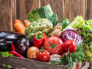 Fresh multi-colored vegetables in wooden crate. Wooden background.