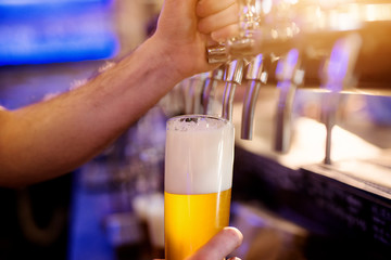 Close up focus view of waiter hands pouring draft beer.