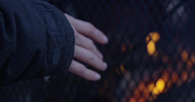 Woman warming hands by outdoor fire pit in winter - close up