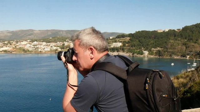 tourist photographs a panorama of a place by the sea
