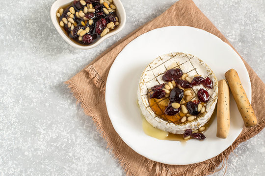 Baked brie cheese with dried cranberries and nuts sauce