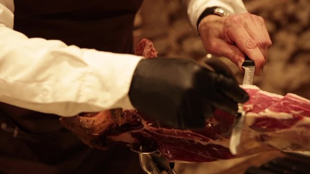 Professional hands slicing iberico spanish ham in a restaurant or event.
