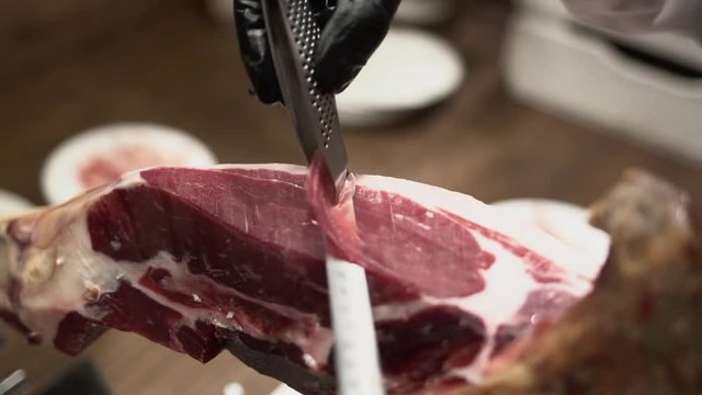 Professional hands slicing iberico spanish ham in a restaurant or event.