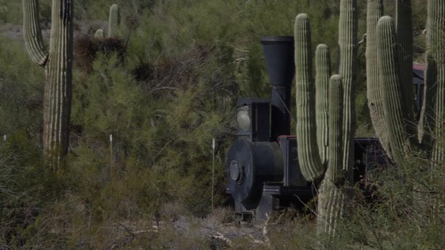 Old west train steam engine on the rails in cactus filled desert