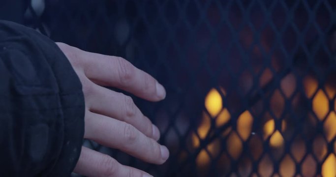 Woman warming hands by outdoor fire pit in winter - extreme close up on fingers