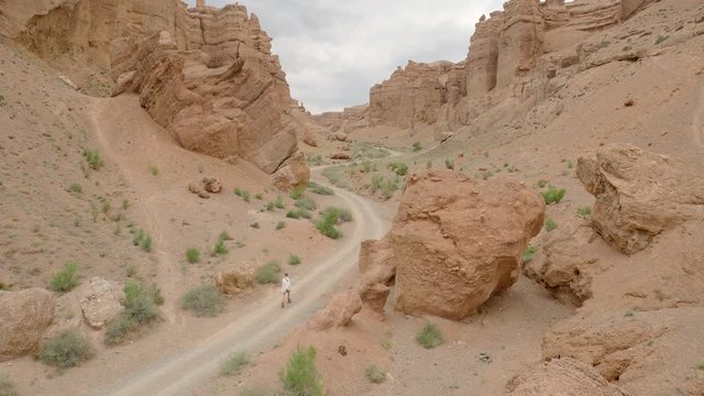 Woman walking down deserted lonely road in desert of Kazakhstan