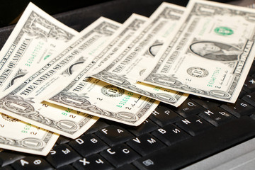 American dollars lie on the laptop keyboard