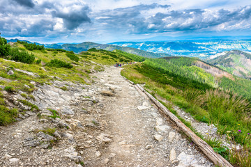 Trail for hiking in mountains, group of distant people, landscap