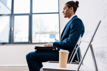 Businessman sitting on chair and waiting by coffee cup