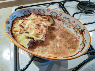 The meat is baked with onions and potatoes in a faience bowl. French cuisine
