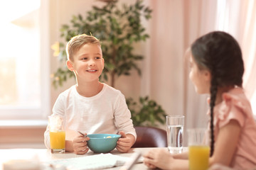 Obraz na płótnie Canvas Happy little children having breakfast in kitchen