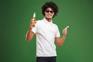 Handsome young african curly man drinking beer make thumbs up.