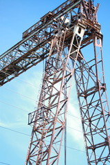Large industrial metal crane on blue sky background.