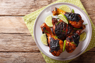 Caribbean grilled chicken drumstick with lime and onions closeup on a plate. horizontal top view from above