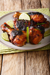 Grilled jerk chicken drumstick with lime and onions closeup on a table. vertical