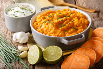 Freshly prepared mashed sweet potatoes with herbs, garlic and lime close up in a pot. horizontal