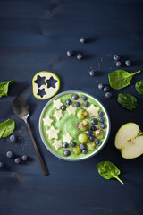 healthy green spinach smoothie bowl with blueberry, banana stars, kiwi, chia seed