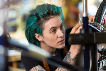 Confident young woman working in a bicycle repair shop
