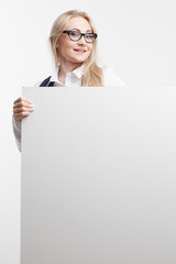 Smiling business woman showing thumb up holds white sign board, advertising banner. Isolated studio portrait.