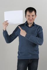 A young man holds a white sheet of paper