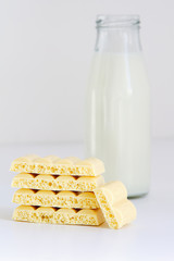 a bottle of milk and a pyramid of white porous chocolate on a white background